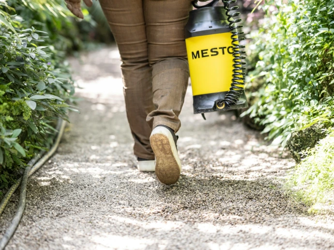 Person walks down a path with a sprayer